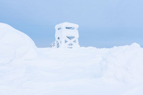 Photo of Iso Pyhätunturi lookout tower covered with snow and frost on a winter day in Salla National Park, Northern Finland.