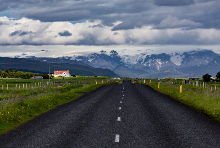 photo of road in South Iceland around Hvolsvöllur area with snowy mountains in the background during summer.