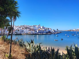 Photo of beautiful aerial view of the sandy beach surrounded by typical white houses in a sunny spring day, Carvoeiro, Lagoa, Algarve, Portugal.