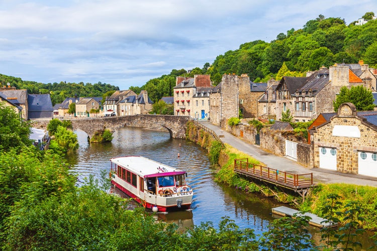 photo of view of panoramic view of old stone bridge and historical medieval houses reflecting in La Rance river in Dinan town - tourist boat in navigation, Dinan, France.