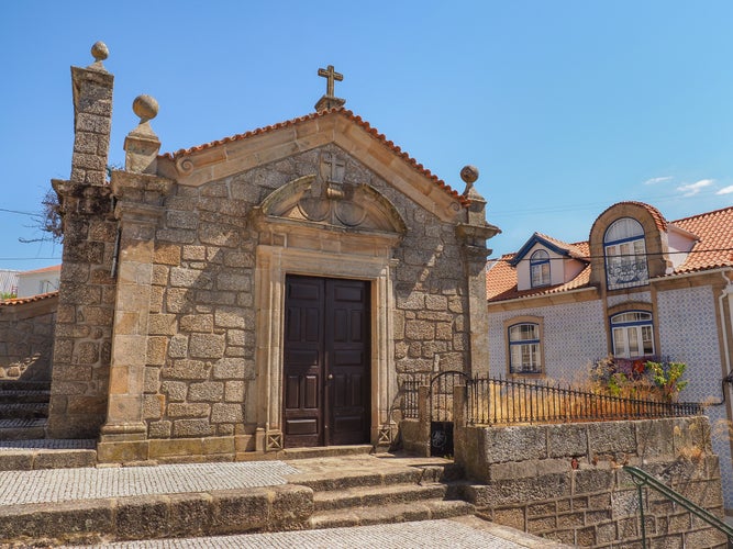 Small catholic Church or Capela de São Silvestre, Covilha, Portugal. Beautiful facade of a stone masonry mannerist chapel with wooden door, cross and bell tower.