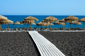 Photo of aerial view of black Perissa beach with beautiful turquoise water, sea waves and straw umbrellas, Greece.