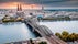 Cologne Aerial view with trains move on a bridge over the Rhine River on which cargo barges and passenger ships ply. Majestic Cologne Cathedral in the background.