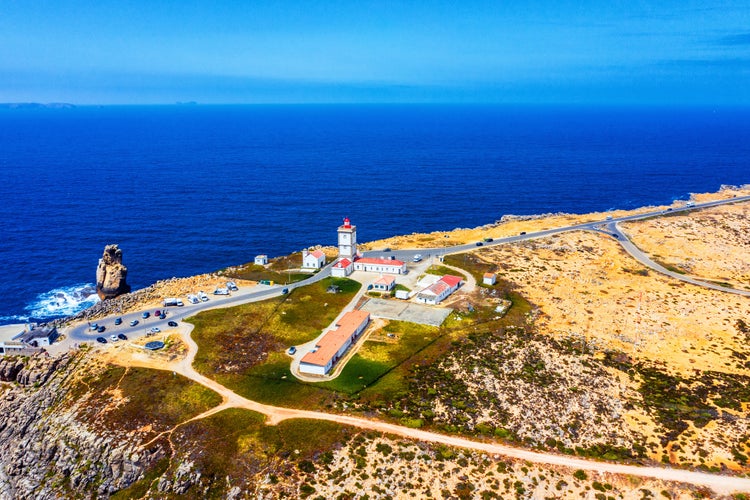 Photo of aerial view of the lighthouse at Peniche with beach, Portugal with cars and ocean.