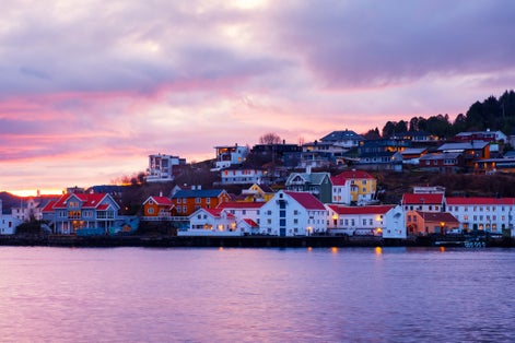 photo of view of Kristiansund, Norway. View of city center of Kristiansund, Norway during the cloudy morning at sunrise with colorful sky. Port with historical buildings