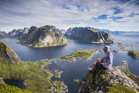 Lofoten, Norway. A view of Reine (Lofoten Island) from the top of Reinebringen. Young guy looking at the landscape.