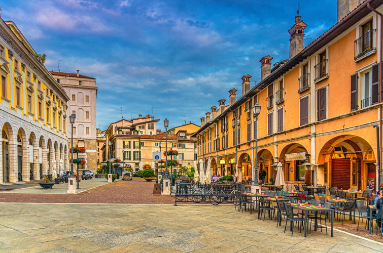 photo of view of Typical italian buildings and tables of street restaurants on Piazza del Mercato, Brescia, Italy.