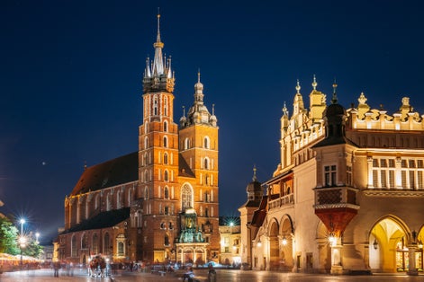 Krakow, Poland. Evening Night View Of The St. Mary's Basilica And Cloth Hall Building. Famous Old Landmark Church Of Our Lady Assumed Into Heaven. Saint Mary's Church. UNESCO World Heritage Site.
