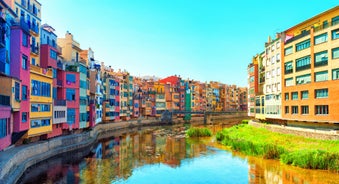 Photo of colorful yellow and orange houses and Eiffel Bridge, Old fish stalls, reflected in water river Onyar, in Girona, Catalonia, Spain.