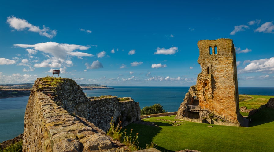 Wide angle shot of the medieval Scarborough Castle during sunset golden hour against a bright blue sky, Yorkshire, England, UK