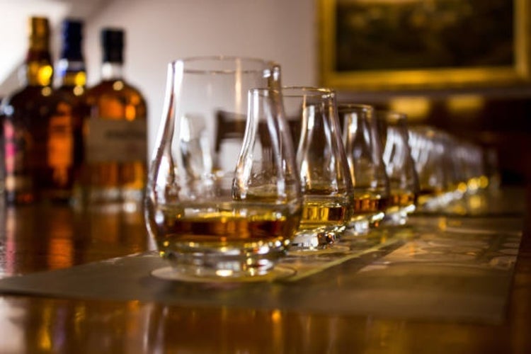 A row of tasting glasses filled with various types of whiskies, arranged neatly for a whisky tasting experience.jpg