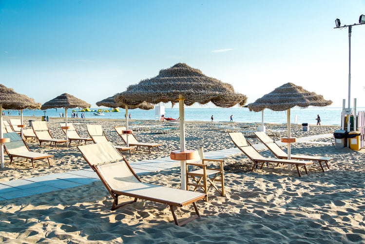 Photo of Umbrellas and chaise lounges on the beautiful beach of Rimini in Italy.