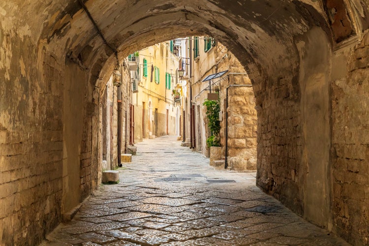 Photo of Stone arch over narrow cobblestone street Andria,Italy.