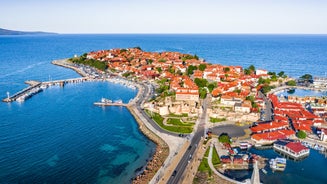 Photo of Saint Anastasia Island in Burgas bay, Black Sea, Bulgaria. Lighthouse tower and old wooden buildings on rocky coast.