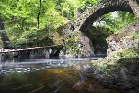 Photo of The Hermitage Bridge in Perthshire Scotland with river flowing through in long exposure .