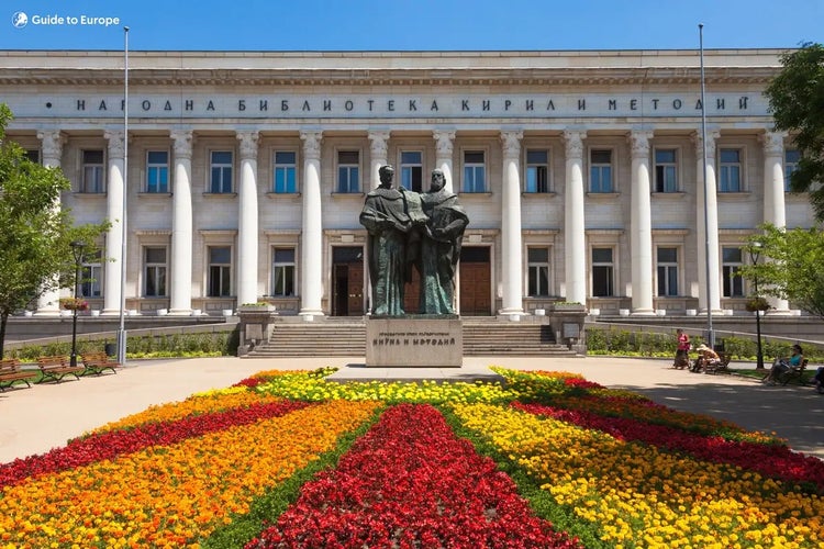 Statue of Saints Cyril and Methodius in front of the National Library in Sofia, Bulgaria, with flower beds and neoclassical architecture..jpg