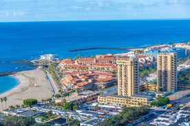 photo of aerial shot of Costa Adeje area, South Tenerife, Spain. Captured at golden hour, warm and vivid sunset colors. Luxury hotels, villas and restaurants behind the beach.