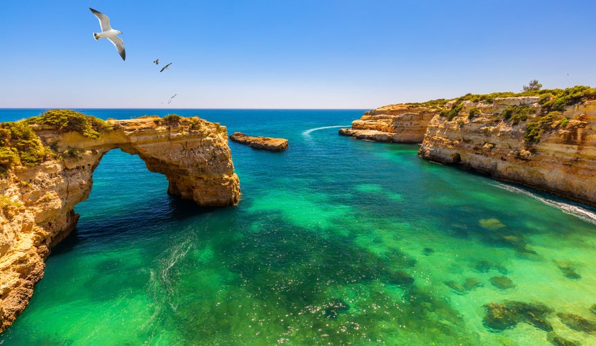 Photo of Natural arch above ocean, Arco de Albandeira, Algarve, Portugal. Stone arch at Praia de Albandeira, Lagoa, Algarve, Portugal. View of the natural arch Arco da Albandeira in the Algarve, Portugal.