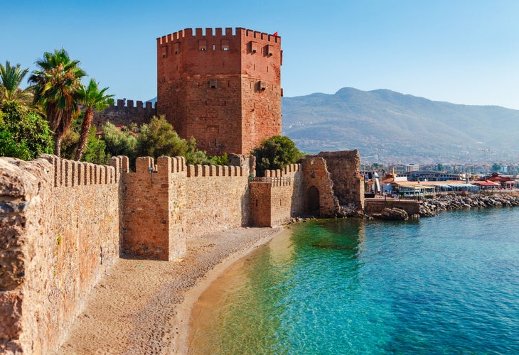 Photo of Kizil Kule tower in Alanya peninsula with beach view, Antalya district, Turkey, Asia. Famous tourist destination with high mountains.