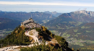 photo of Elevated, scenic view of the town of Bischofswiesen, Bavaria, Germany. The Watzmann Mountain, part of the Bavarian Alps rises into a majestic skyline. A green, spring landscape set in the valley.