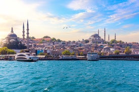 Touristic sightseeing ships in Golden Horn bay of Istanbul and mosque with Sultanahmet district against blue sky and clouds. Istanbul, Turkey during sunny summer day.