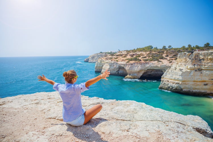 Photo of happy tourist girl looking out on the ocean. Lagos, Algarve Coast, Portugal.