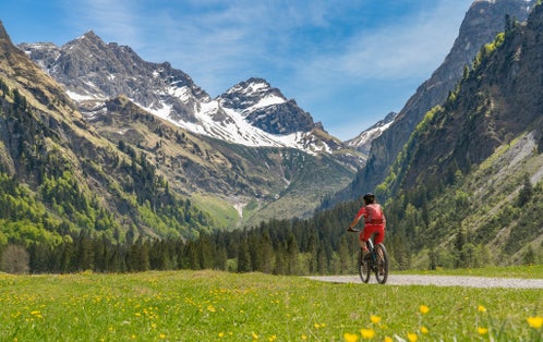Photo of pretty senior woman riding her electric mountain bike the Oy Tal Valley near Oberstdorf, Allgau Alps, Bavaria, Germany