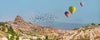 photo of hot air balloon flying over spectacular Uchisar castle and Pigeon valley in Cappadocia, Turkey.