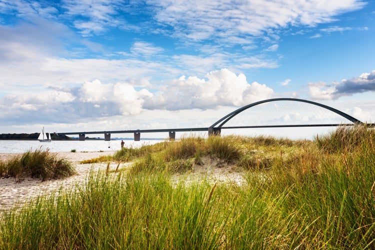 Photo of Fehmarn sound bridge. Late summer landscape with beach, dune grass and cloudy sky. Vacation background. Baltic sea coast, Germany, travel destination.