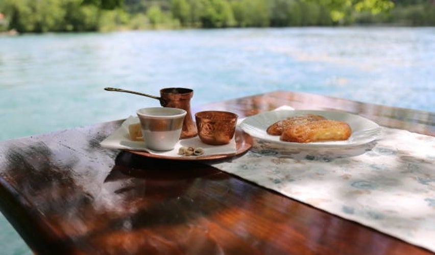 Traditional Bosnian coffee served with cake on a table by the river bank.jpg