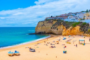 Photo of beautiful aerial view of the sandy beach surrounded by typical white houses in a sunny spring day, Carvoeiro, Lagoa, Algarve, Portugal.