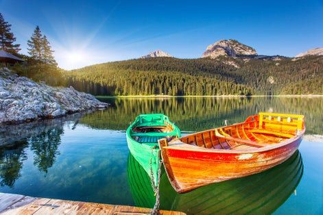 Photo of reflection in water of mountain lakes and boats. Black lake in Durmitor national park in Montenegro.