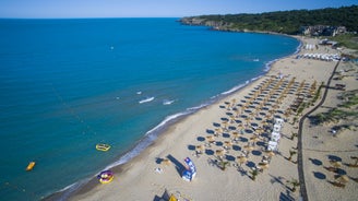 Photo of Saint Anastasia Island in Burgas bay, Black Sea, Bulgaria. Lighthouse tower and old wooden buildings on rocky coast.