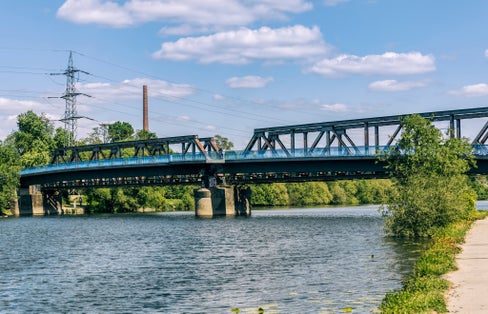 Photo of Ruhr River with old railroad bridge and modern footbridge in Bochum, Germany.