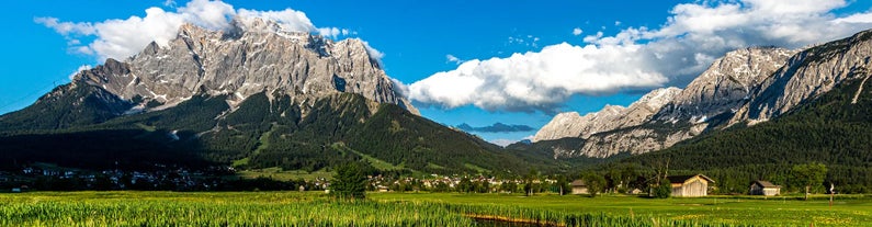 Photo of a view of the Alps from the Ehrwald, a town on the border of Germany and Austria with picturesque meadows surrounded by towering mountain ranges, including the Zugspitze.