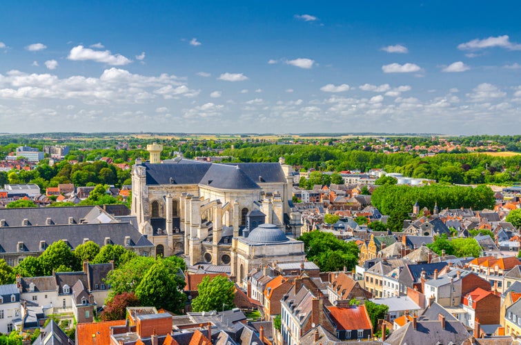 Aerial panoramic view of Arras city historical town centre, Arras Cathedral of Our Lady and Saint Vaast catholic church, green parks and fields on horizon, blue sky, Pas-de-Calais department, France