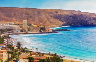 photo of aerial shot of Costa Adeje area, South Tenerife, Spain. Captured at golden hour, warm and vivid sunset colors. Luxury hotels, villas and restaurants behind the beach.