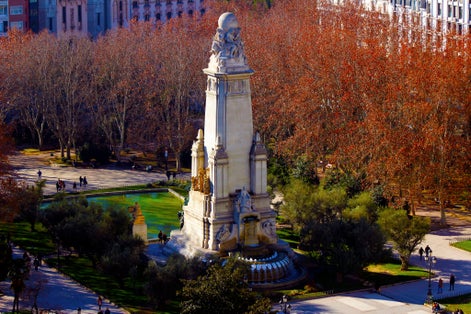 Photo of A view from above of people walking around the Miguel de Cervantes monument in the so called Spain Square. The photo shot is taken in the city center of Madrid, Europe. 