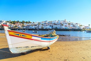 Photo of beautiful aerial view of the sandy beach surrounded by typical white houses in a sunny spring day, Carvoeiro, Lagoa, Algarve, Portugal.