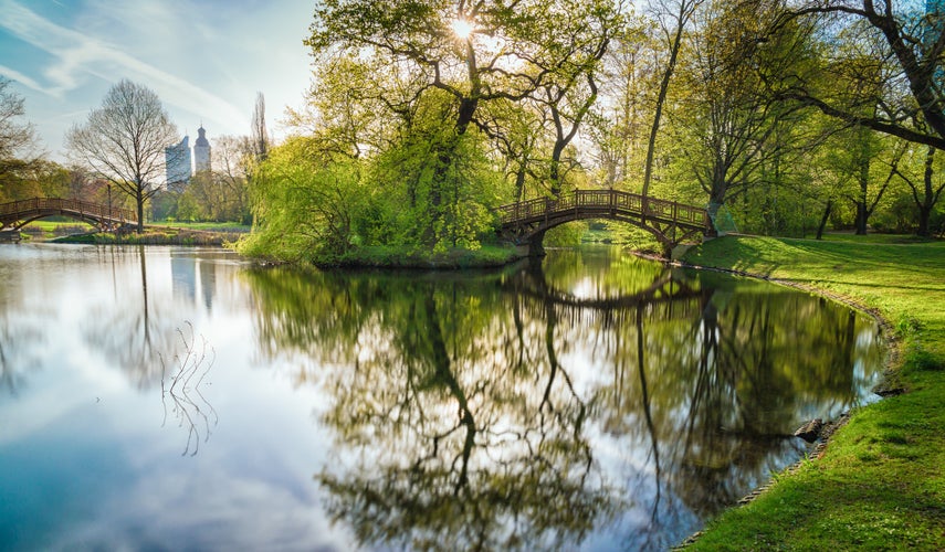 Photo of wooden bridge with a mirroring lake in Johanna Park Leipzig.