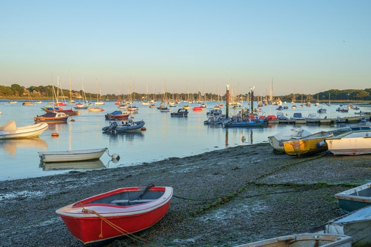 Rowing boats and yachts at Itchenor, Chichester Harbour, in the evening light at low tide.