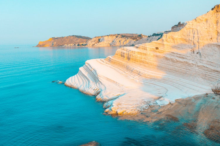 Photo of sandy beach under famed white cliff, called "Scala dei Turchi", in Sicily, near Agrigento, Italy.