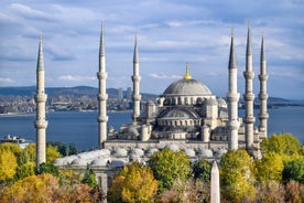 Touristic sightseeing ships in Golden Horn bay of Istanbul and mosque with Sultanahmet district against blue sky and clouds. Istanbul, Turkey during sunny summer day.