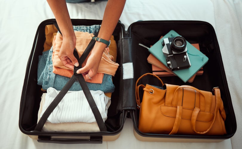 Travel suitcase, bedroom and hands of woman packing for Europe holiday.jpg