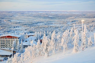 Photo of stunning sunset view over wooden huts and snow covered trees in Kuusamo, Finnish Lapland.