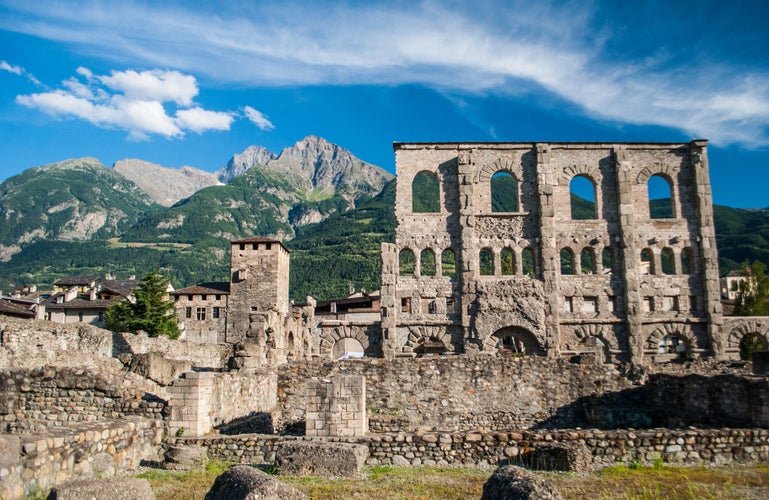 Aosta, Italy - old roman wall ruins and the mountains on a sunny day of summer