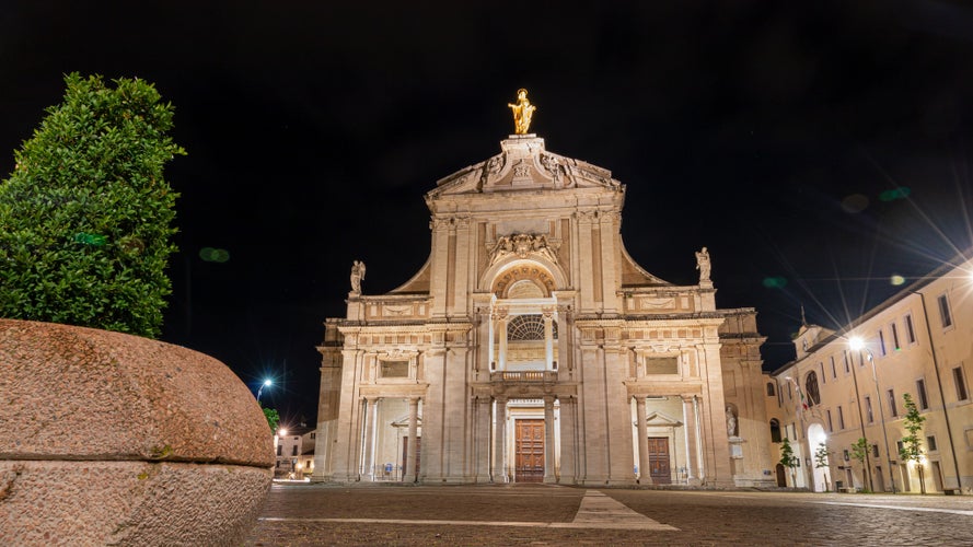 photo of view of iIluminated facade of the Papal Basilica of Saint Mary of the Angels in Santa Maria degli Angeli, Assisi, region of Umbria, Italy.