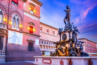 Photo of Italy Piazza Maggiore in Bologna old town tower of town hall with big clock and blue sky on background, antique buildings terracotta galleries.