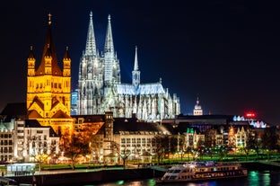 Cologne Aerial view with trains move on a bridge over the Rhine River on which cargo barges and passenger ships ply. Majestic Cologne Cathedral in the background.