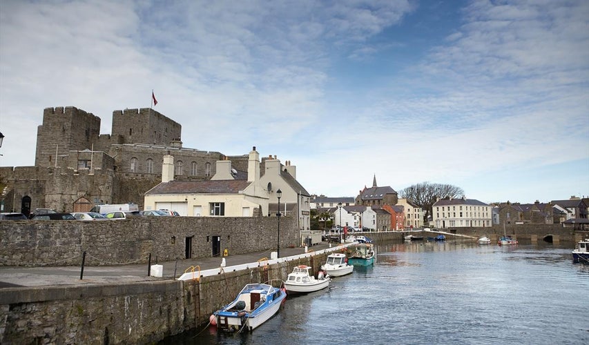 Castle Rushen in Castletown in the Isle of Man, with reflections in the harbor - taken shortly after sunrise